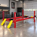 AMGO PRO-12SX Four-Post Lift installed in a professional automotive garage with red posts and yellow approach ramps