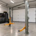 Triumph NTO-11A Overhead Two-Post Lift angled garage view showing overhead structure and orange lifting arms